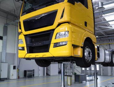 Yellow truck on a lift in a car service. Servicing and repairing trucks in a large garage. Car service, repair, diagnostics.